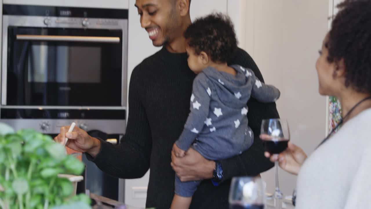 一对夫妇带着小女儿在厨房里做饭喝酒视频素材