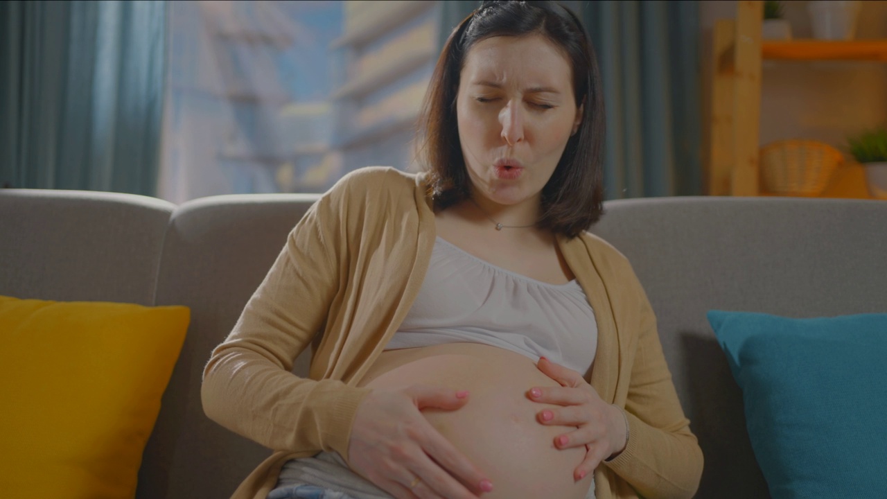 一幅孕妇坐在沙发上分娩时疼痛的画像视频下载