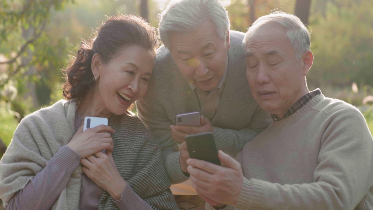 快乐的老人在公园里使用智能手机，4K视频素材