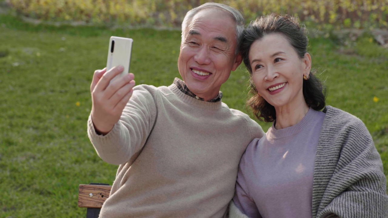 快乐的老夫妇在公园里使用智能手机，4K视频素材