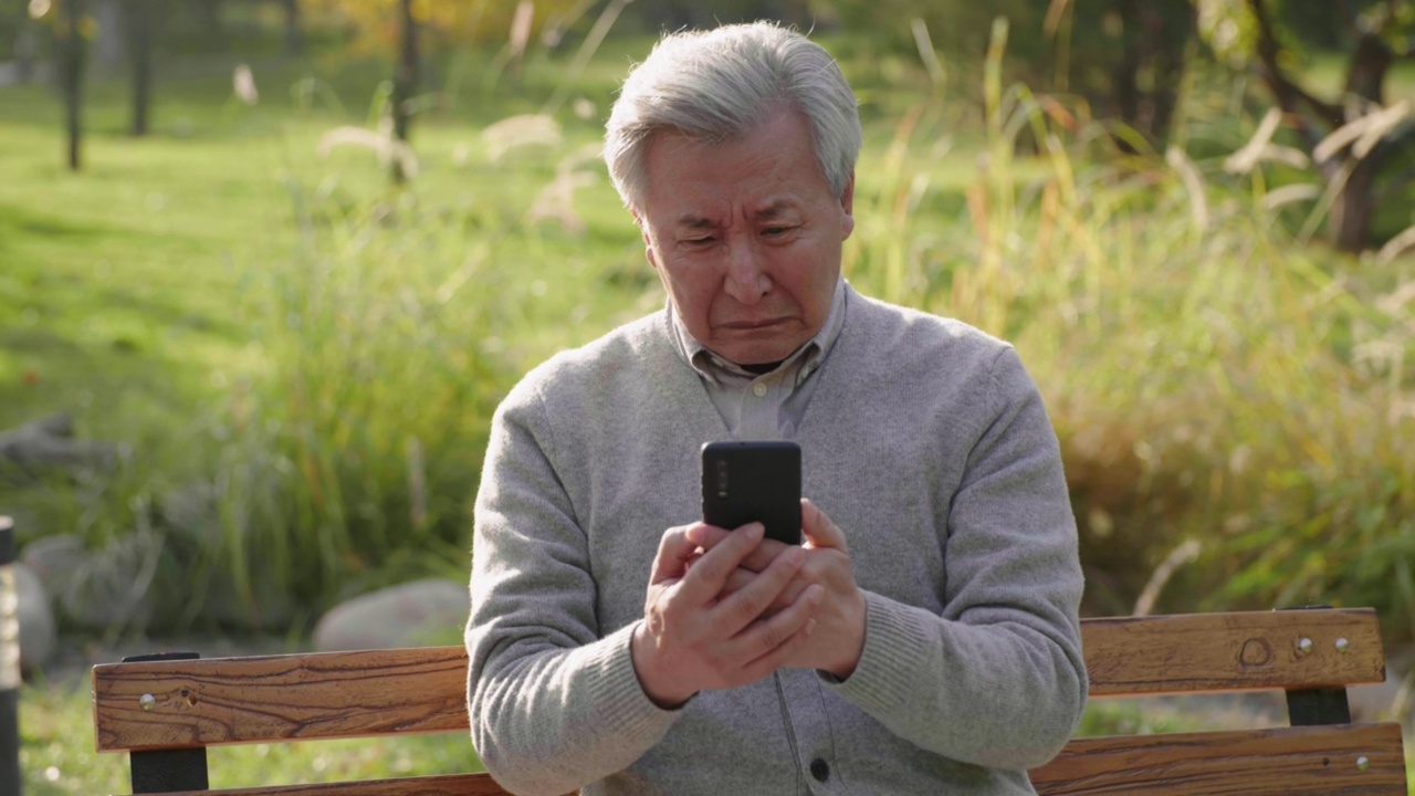 老人在公园用智能手机，4K视频素材