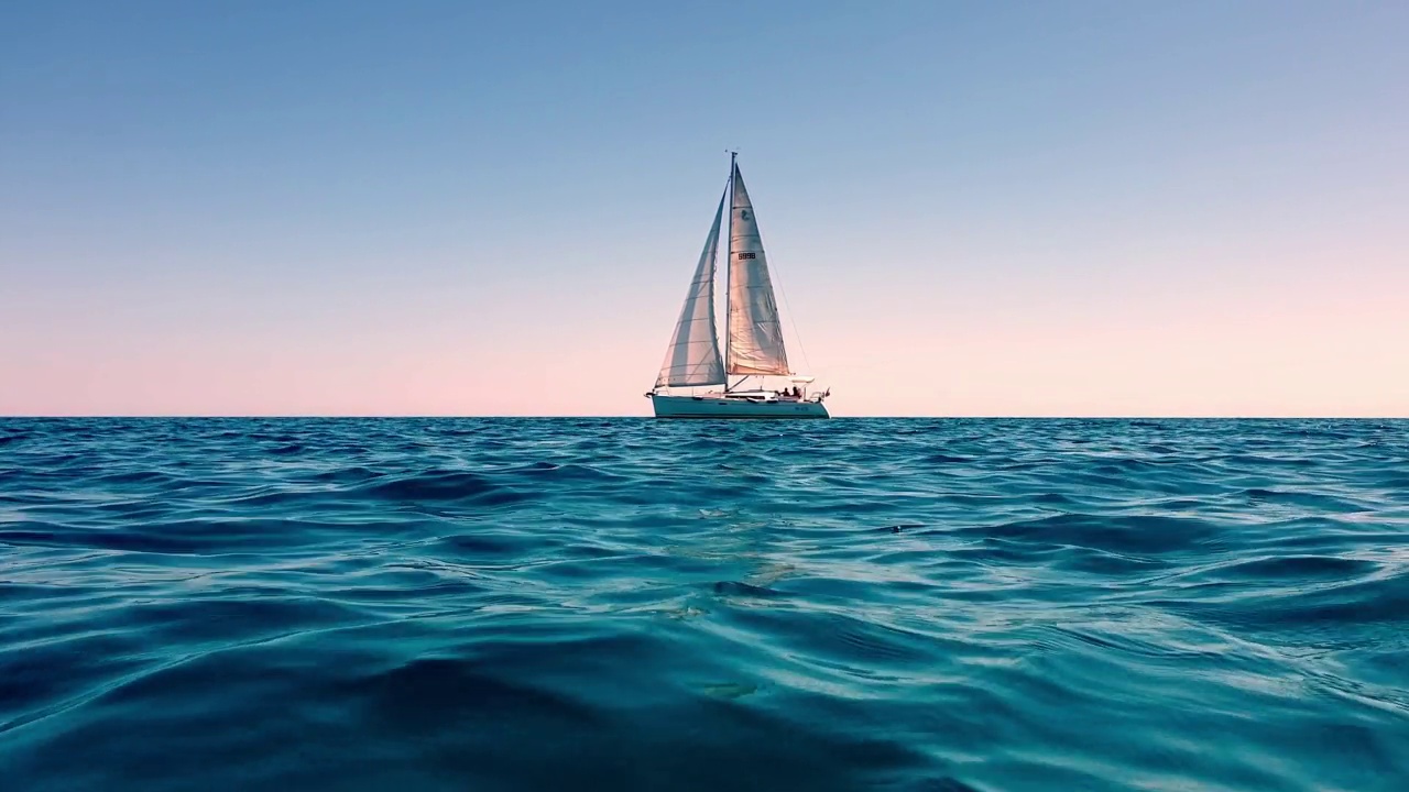 放大和低角度的海平面小游艇航行在平静的开阔海面日落。慢动作视频素材