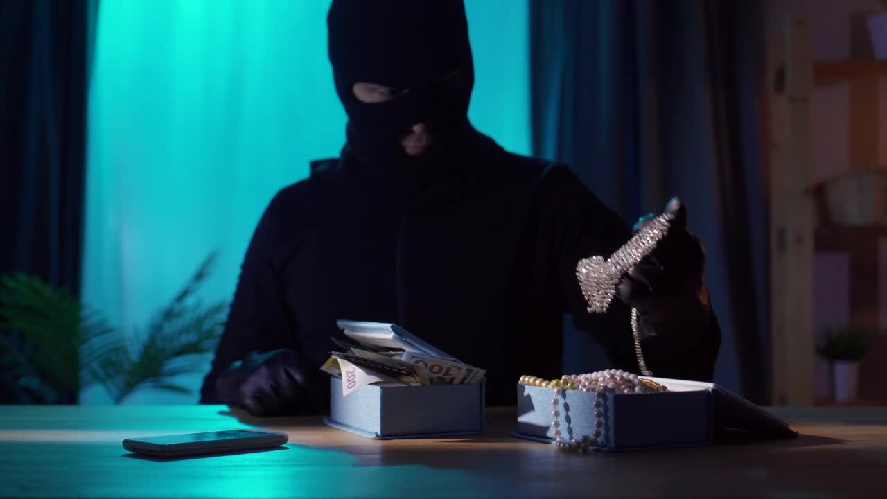 一个强盗的肖像戴着黑色巴拉克拉法帽，手里拿着珠宝视频素材