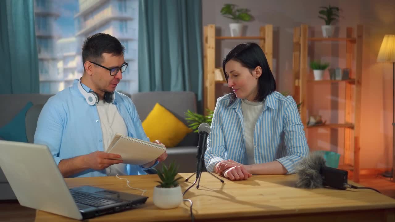戴眼镜的男人和一个女人坐在家庭录音棚里录制播客采访视频下载