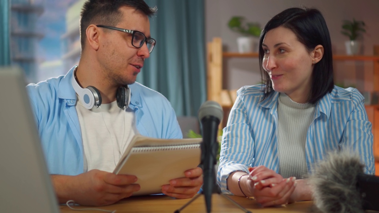 戴眼镜的男人和一个女人坐在家庭录音棚录制播客采访，特写视频下载