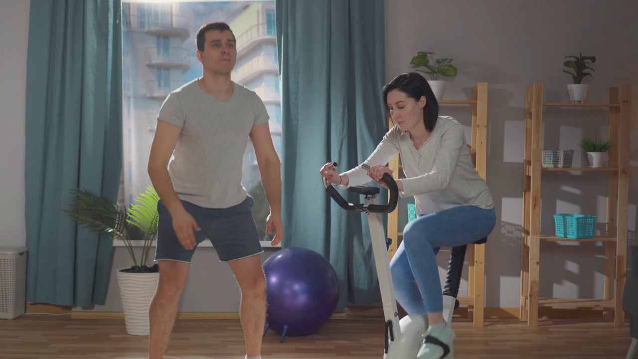 年轻的运动员夫妇在家里的客厅里做运动视频下载