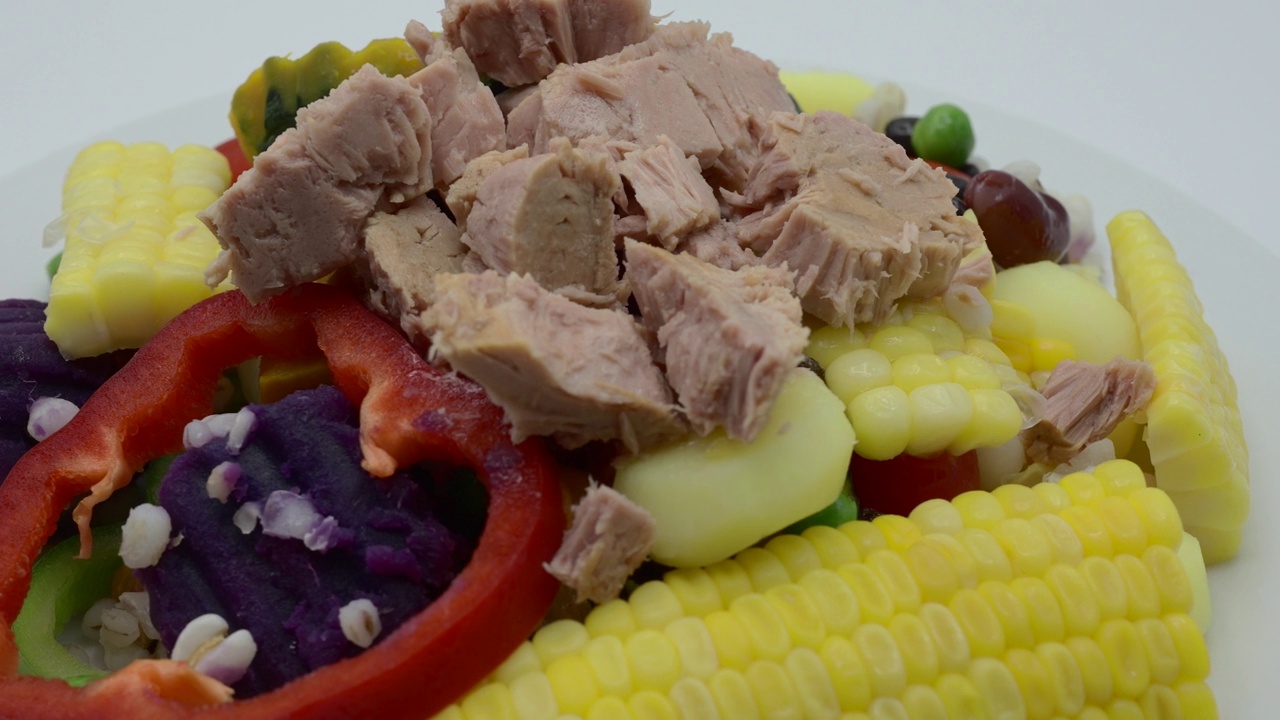 金枪鱼牛排上面的混合蔬菜和豆类旋转在白色镀。视频下载