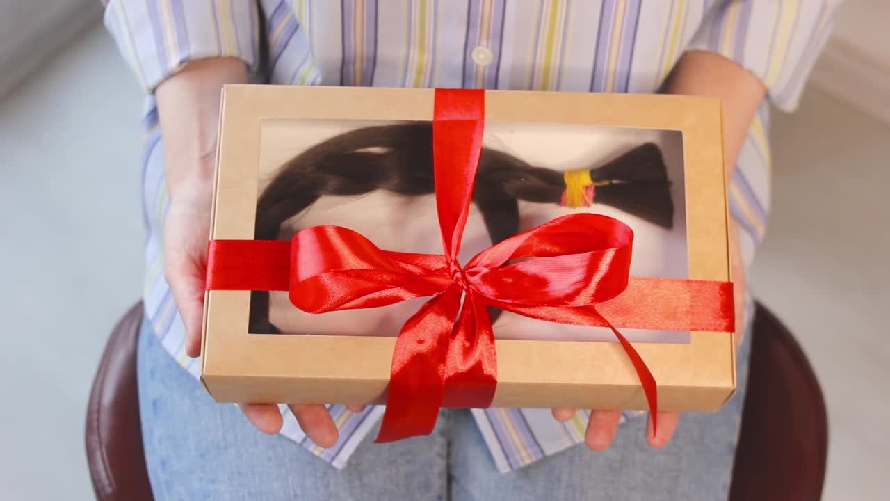女人拿着礼盒，里面有剪长的辫子，捐赠的头发，天然的头发视频下载