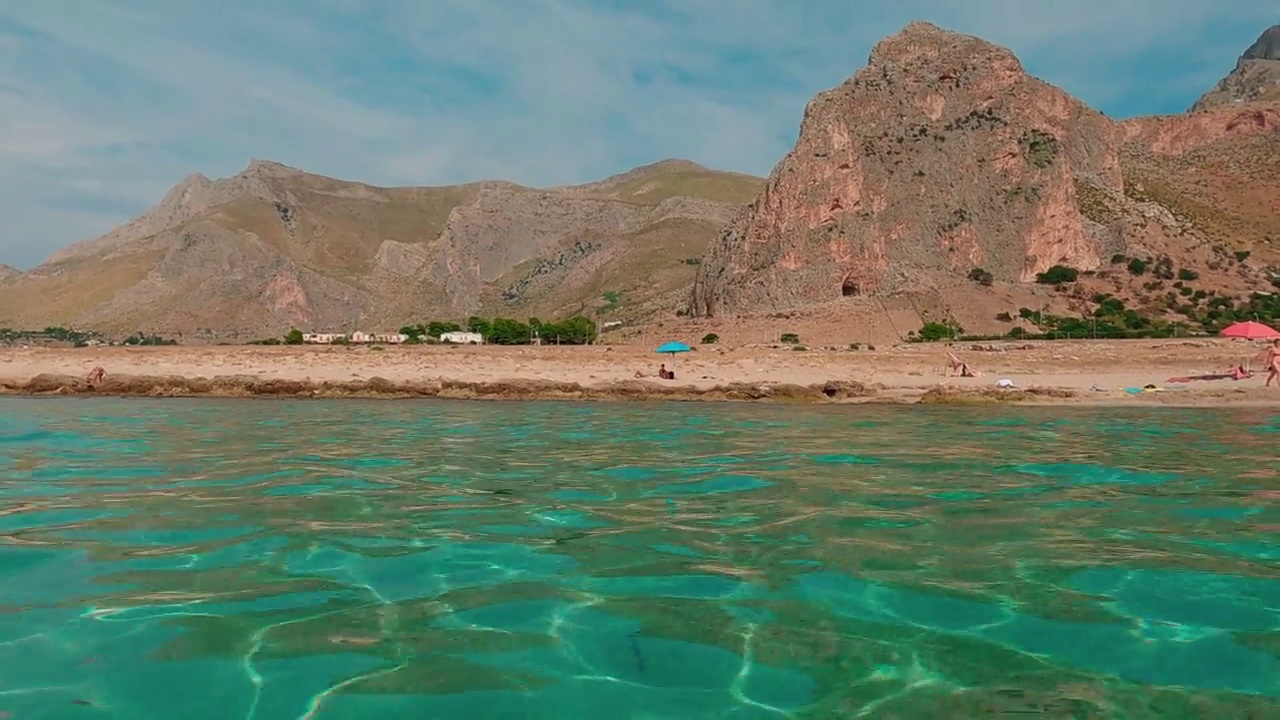 在西西里岛的巴亚圣玛格丽塔和周围的风景中，人们沐浴在蓝绿色的海水中。慢摇上视频素材