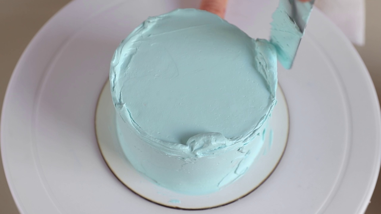糖果师在圆形蛋糕上抹上蓝色奶油视频下载