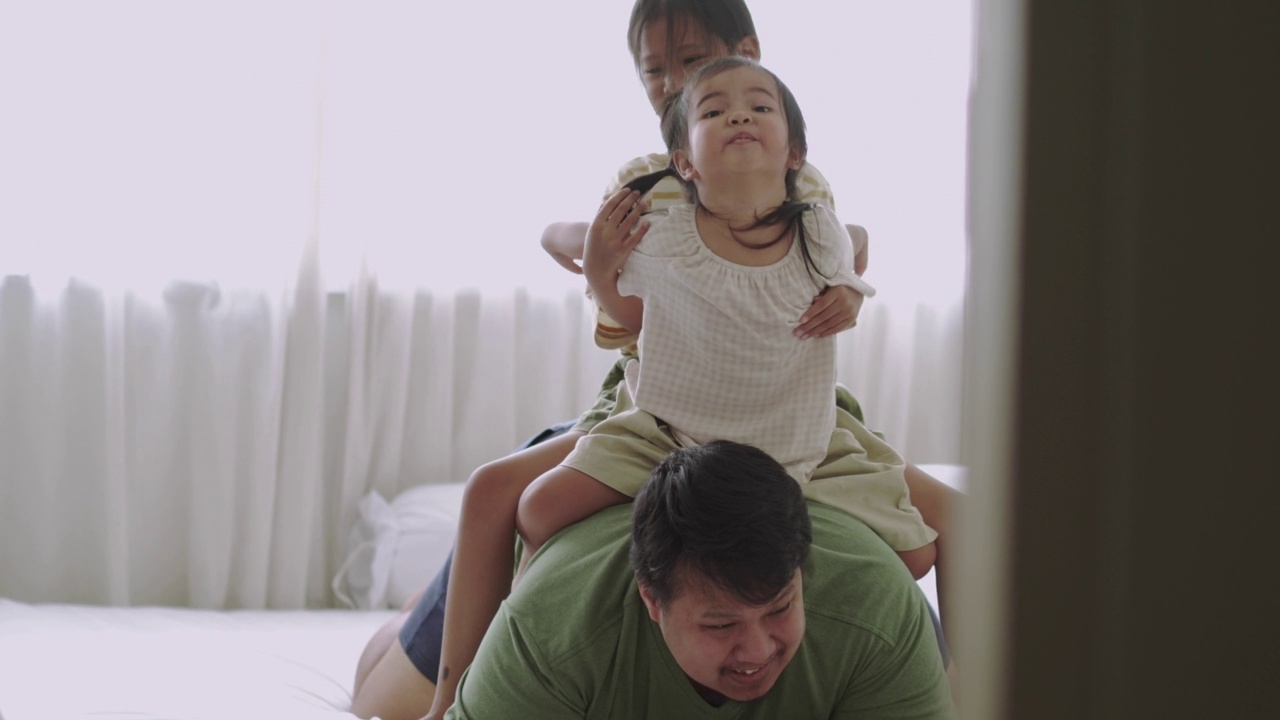 一家人在床上享受，女儿骑在父亲背上玩耍视频下载