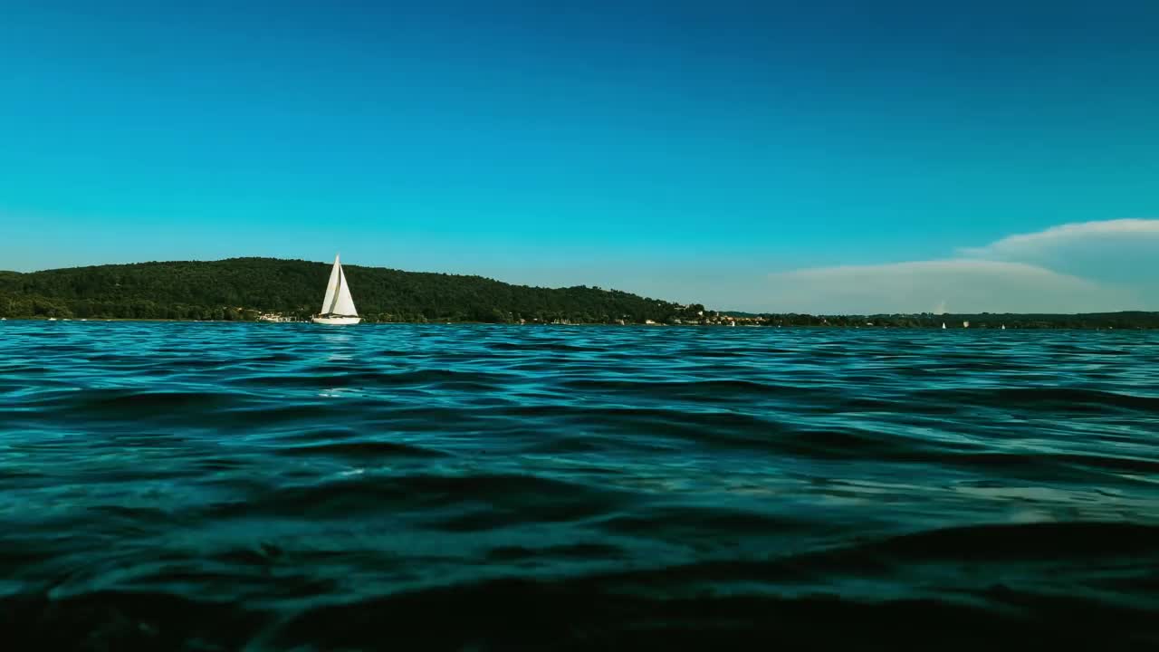 极端低角度蓝绿色的观点小船航行在平静开放的湖面马乔里湖在意大利。慢动作视频素材