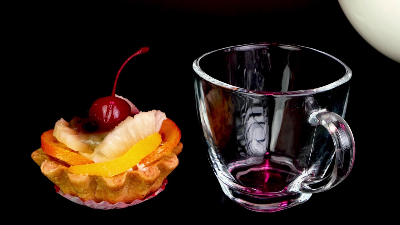 奶油蛋糕与樱桃，浆果，水果和苹果花在黑色的背景。牛奶倒进透明的杯子里。视频下载