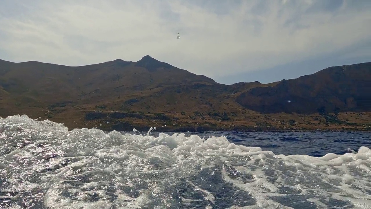 西西里著名的Riserva dello Zingaro自然保护区，从移动的小船上可以看到海景和悬崖景观。平移水面视图视频素材