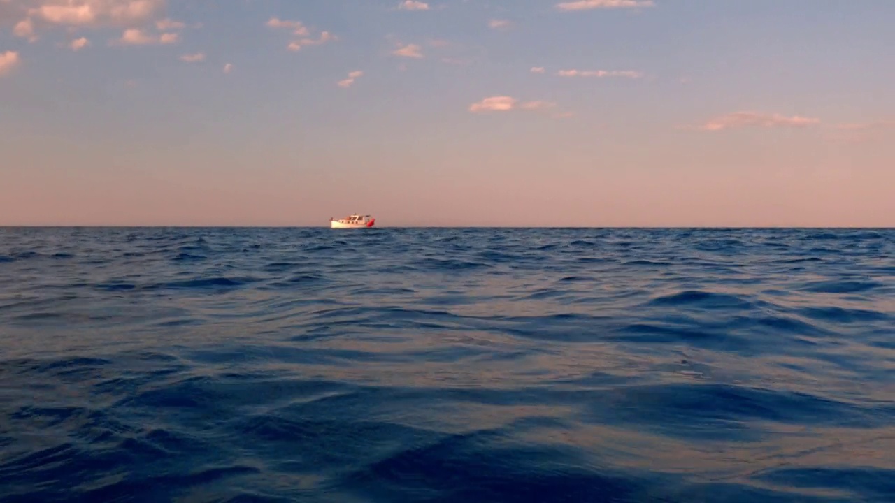 黄昏远海航行孤僻小游艇低角度海面倾角视频素材
