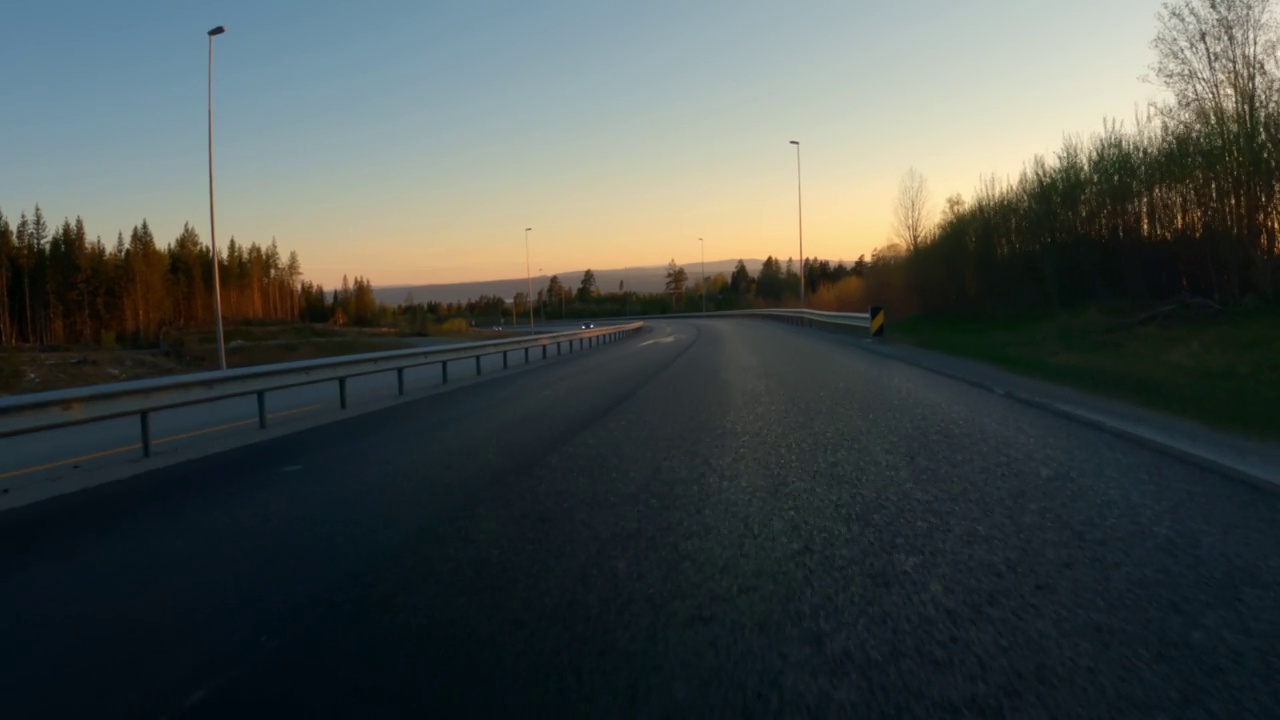 在高速公路上行驶，沿着山往下走，直到夕阳西下。的观点。视频下载
