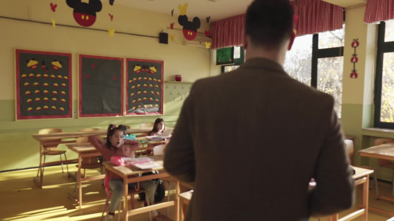 年轻的男老师在小学课堂上帮助男生视频素材