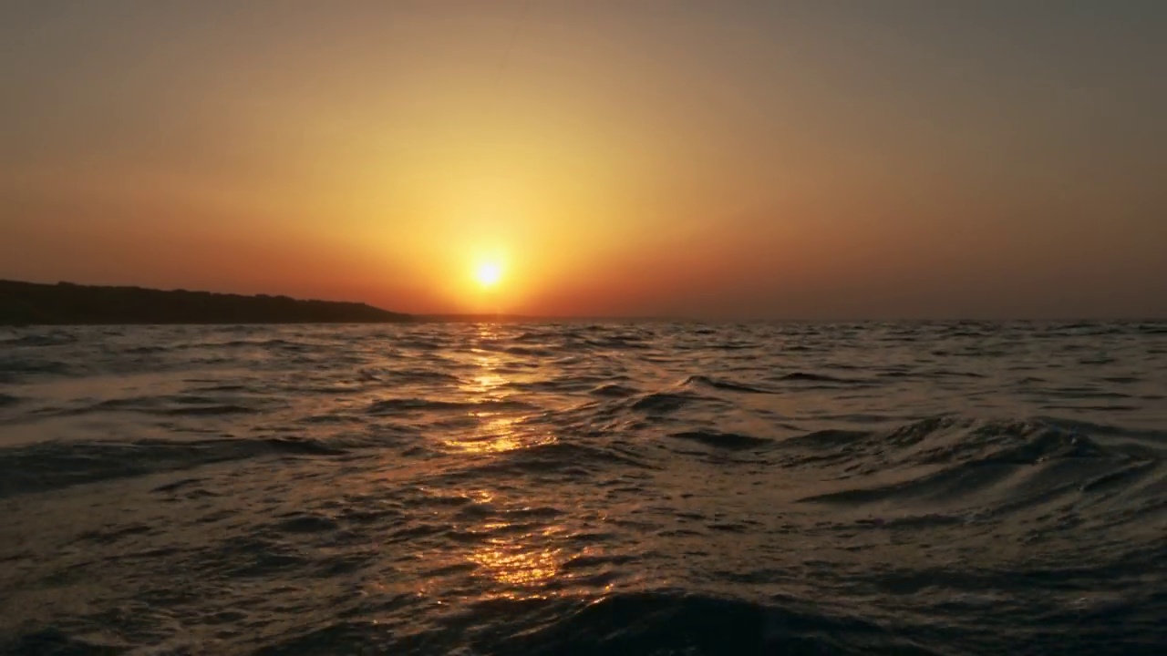 令人惊叹的电影低角度海平面pov从帆船航行在海面上的金色日落。慢动作视频素材