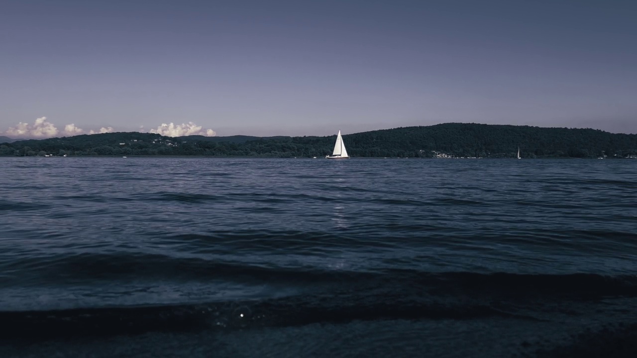 电影般的深色低角度视角的游艇在意大利马乔里湖的平静开放的湖水中巡航。的放大视频素材