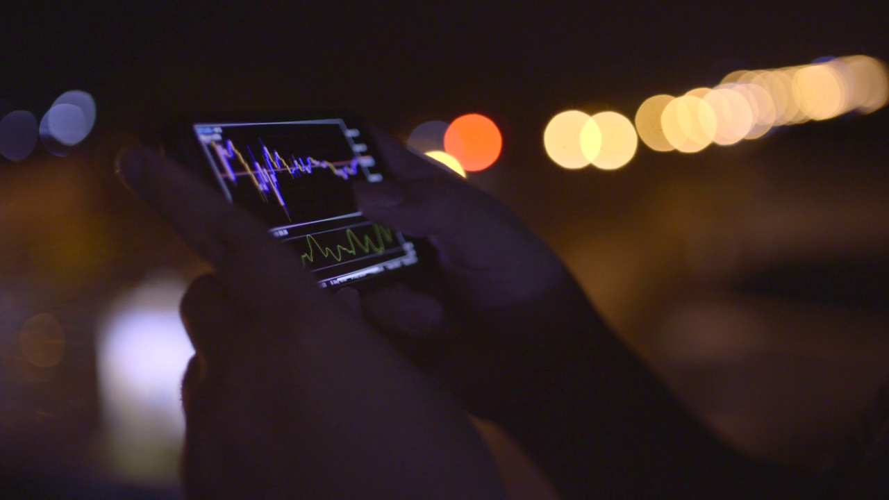 夜间用散光背景在手机上检查股票市场或加密货币数据视频素材