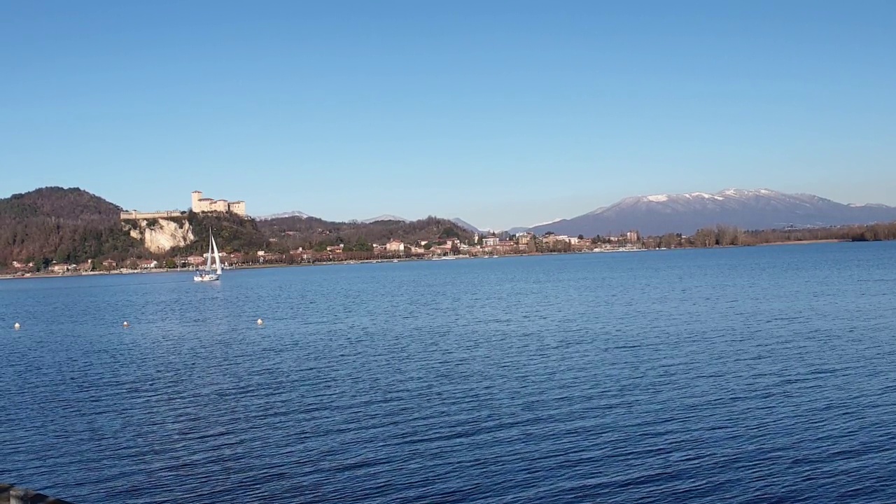小帆船在皮埃蒙特的马乔雷湖上航行，背景是群山和城堡。意大利视频素材