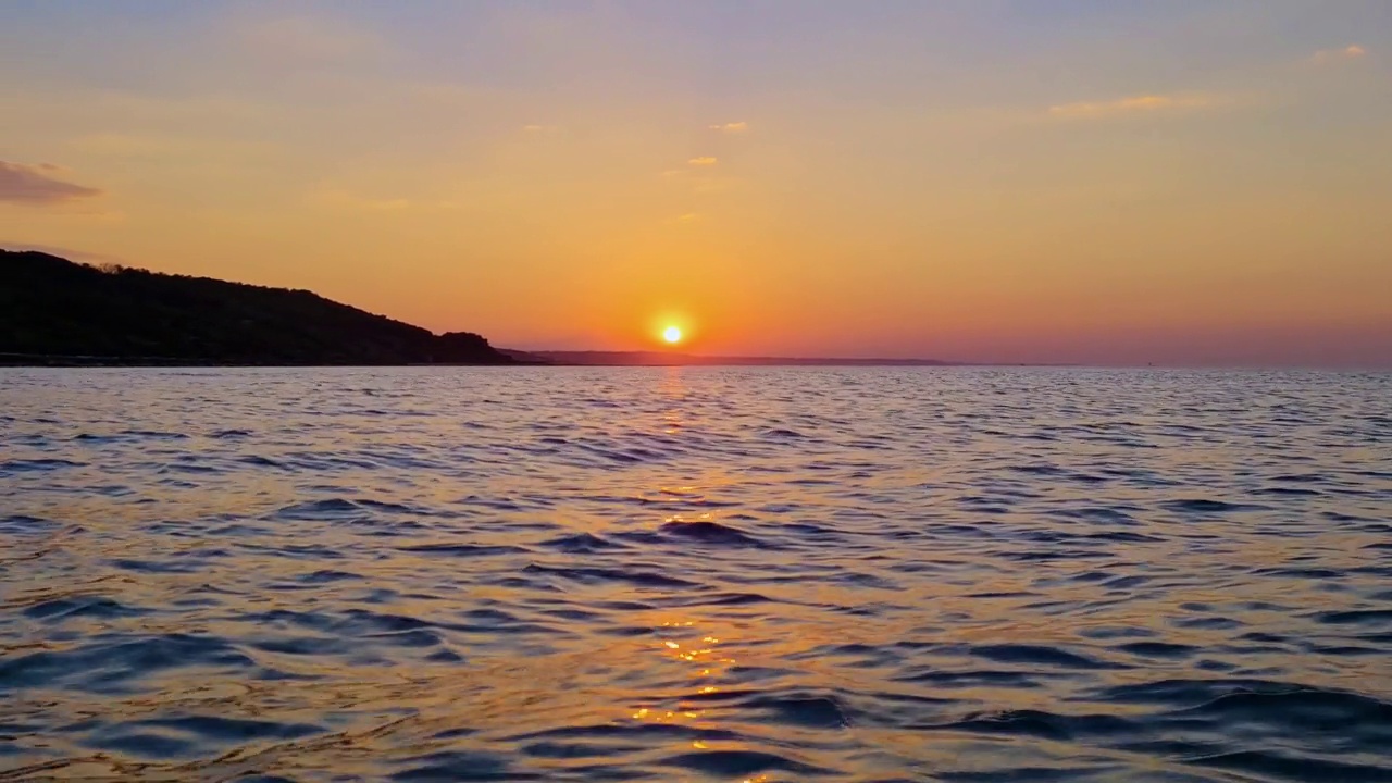 日落时海水表面向后移动的低角度。第一人称视角视频素材