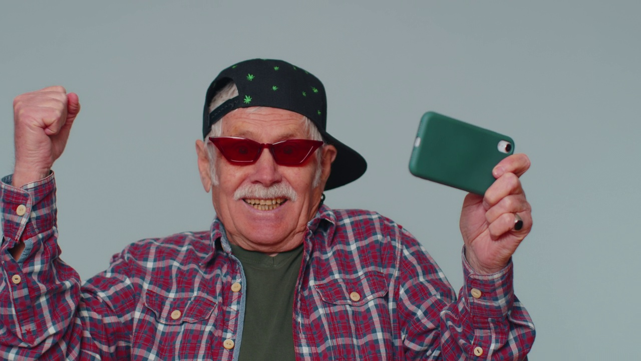 担心有趣上瘾的老人热情地玩着手机上的赛车视频游戏视频素材