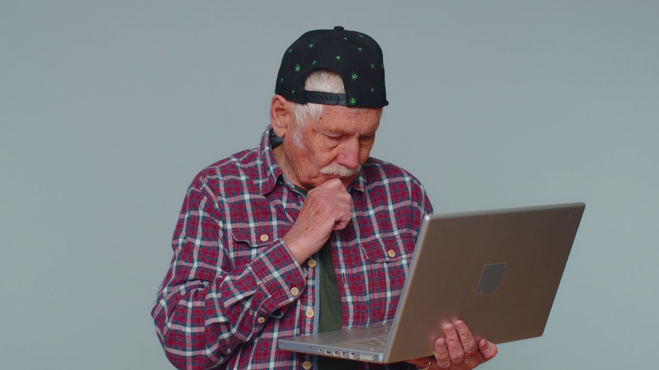 快乐的老人在笔记本电脑上打字，在项目上工作，享受成果，中彩票视频素材