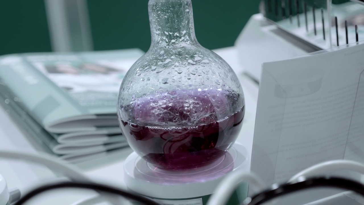 实验室电磁式混合器在玻璃烧瓶中混合一种用于医疗、化工、化妆品行业的黄色溶液。特写镜头。在运动视频素材
