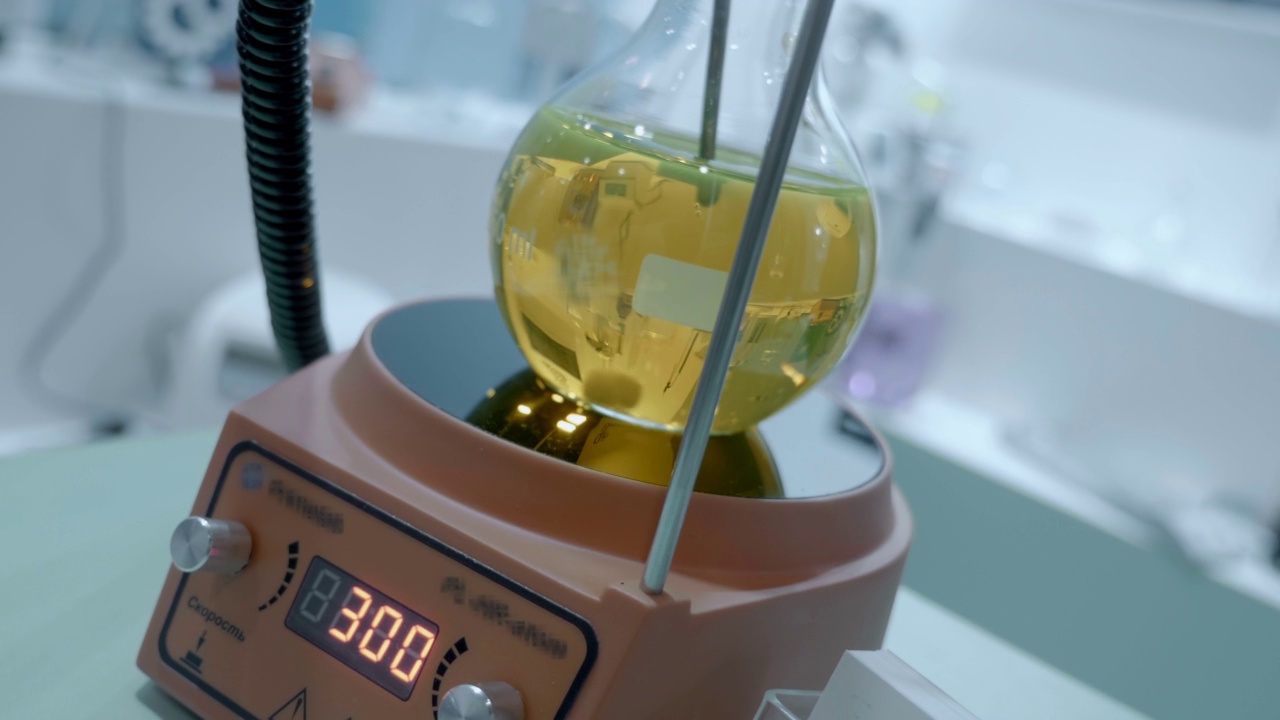 实验室的电磁混合器在玻璃烧瓶中混合一种黄色溶液视频素材