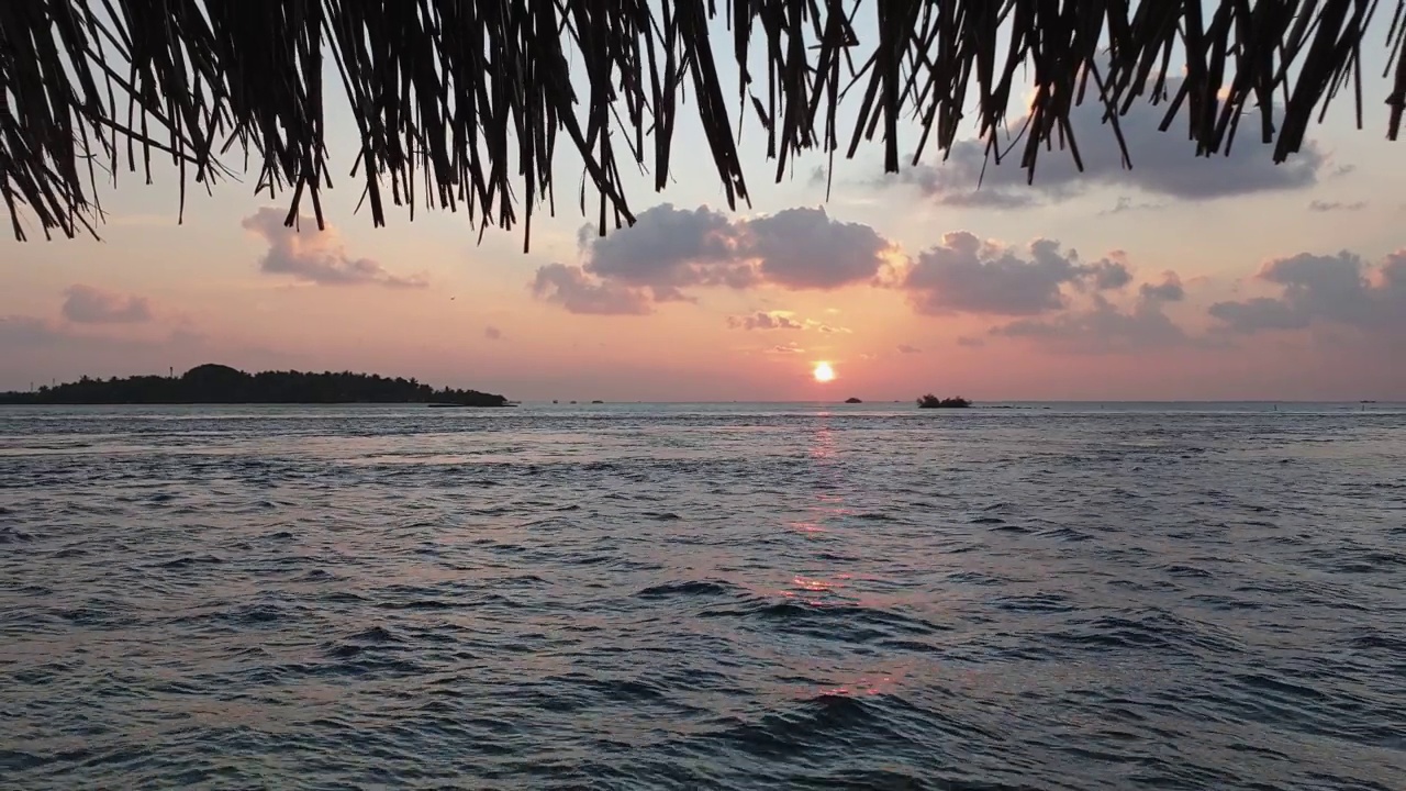 马尔代夫浪漫的夕阳和茅草屋顶的慢动作视频素材