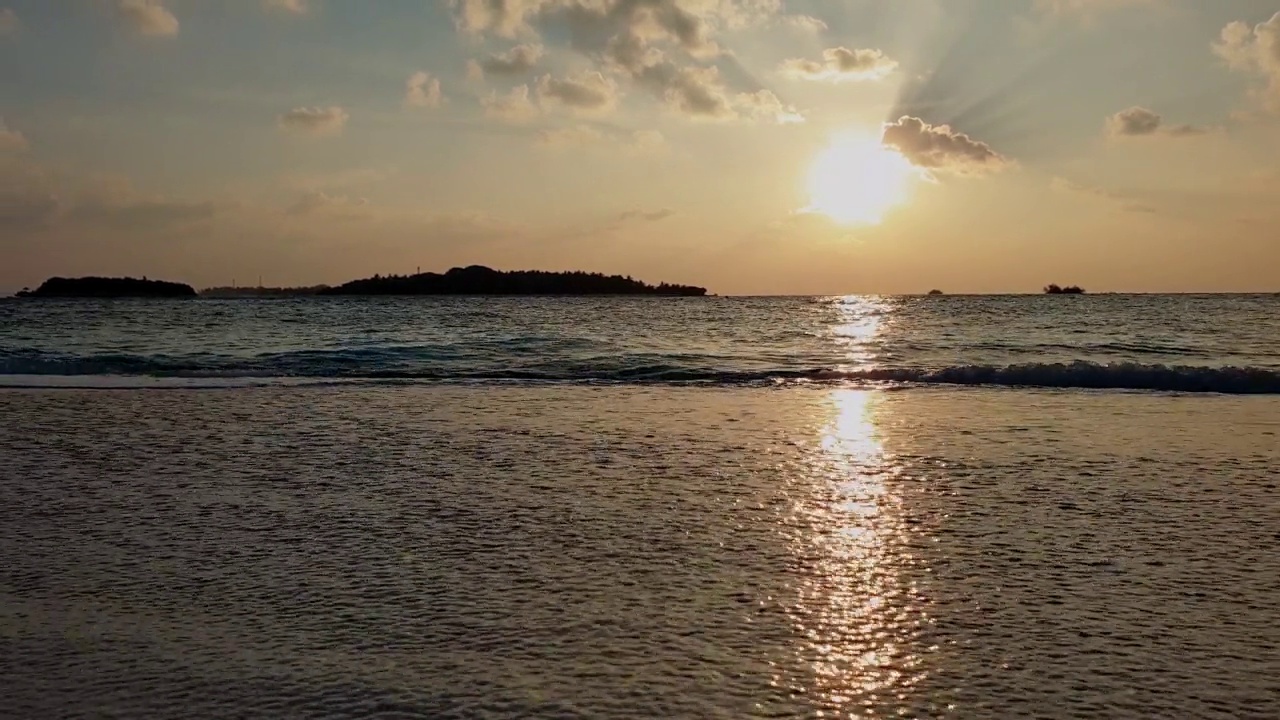 黄昏时分，低角度走向马尔代夫海滩的海滨。慢动作视频素材