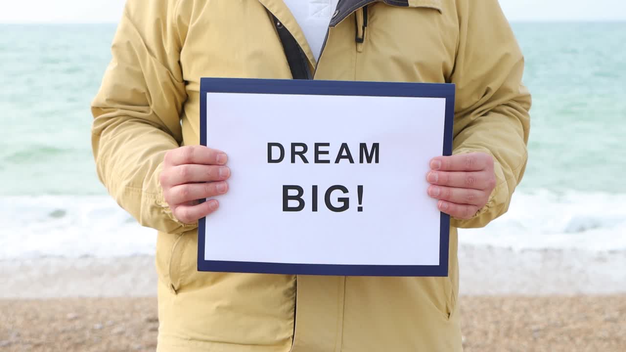 一名男子手持海报，上面写着“梦想远大!”动机概念镜头。视频素材