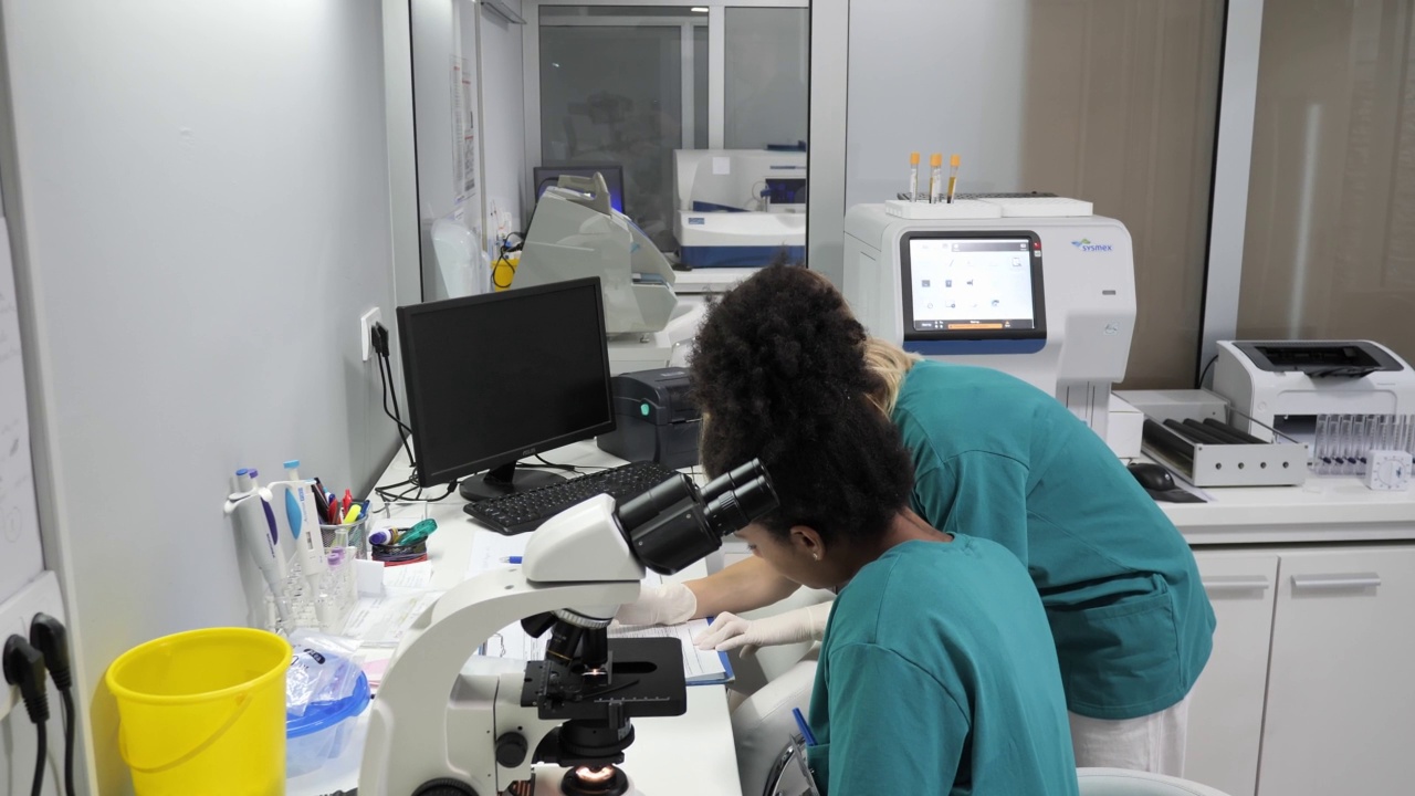 不同的员工在实验室工作。非洲女医生使用显微镜视频下载