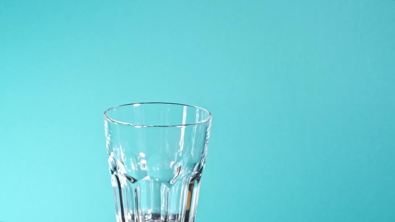 一股水落入一个透明的玻璃杯视频素材