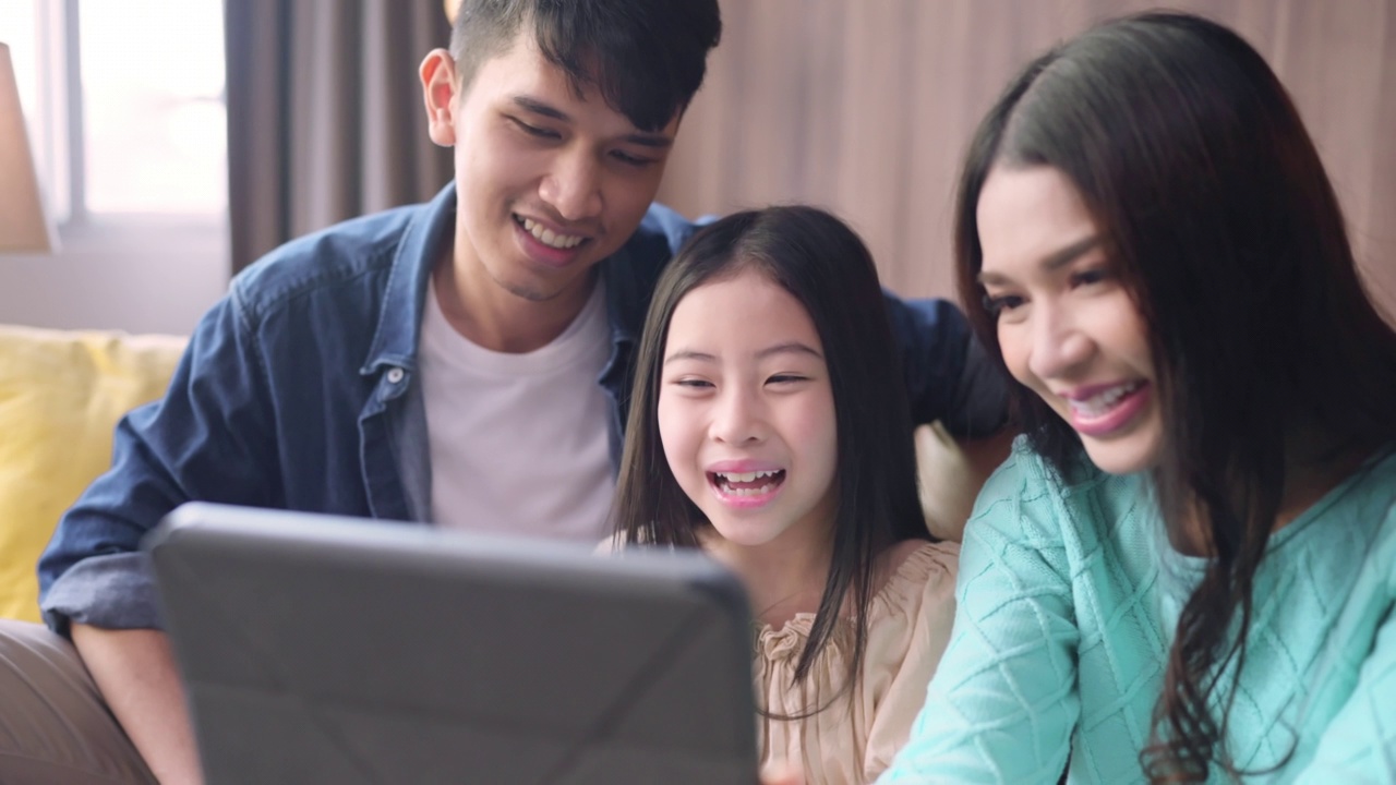 幸福亚洲家庭的女儿呆在一起在家里用平板电脑自拍照片或视频打电话给祖父母距离沟通，自拍家庭的肖像一起在客厅的家视频素材