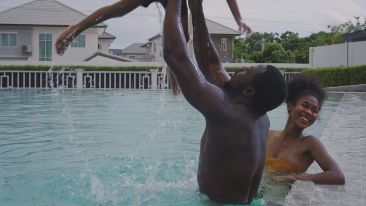 非洲家庭，父亲和母亲带着小男孩在度假村的游泳池视频素材