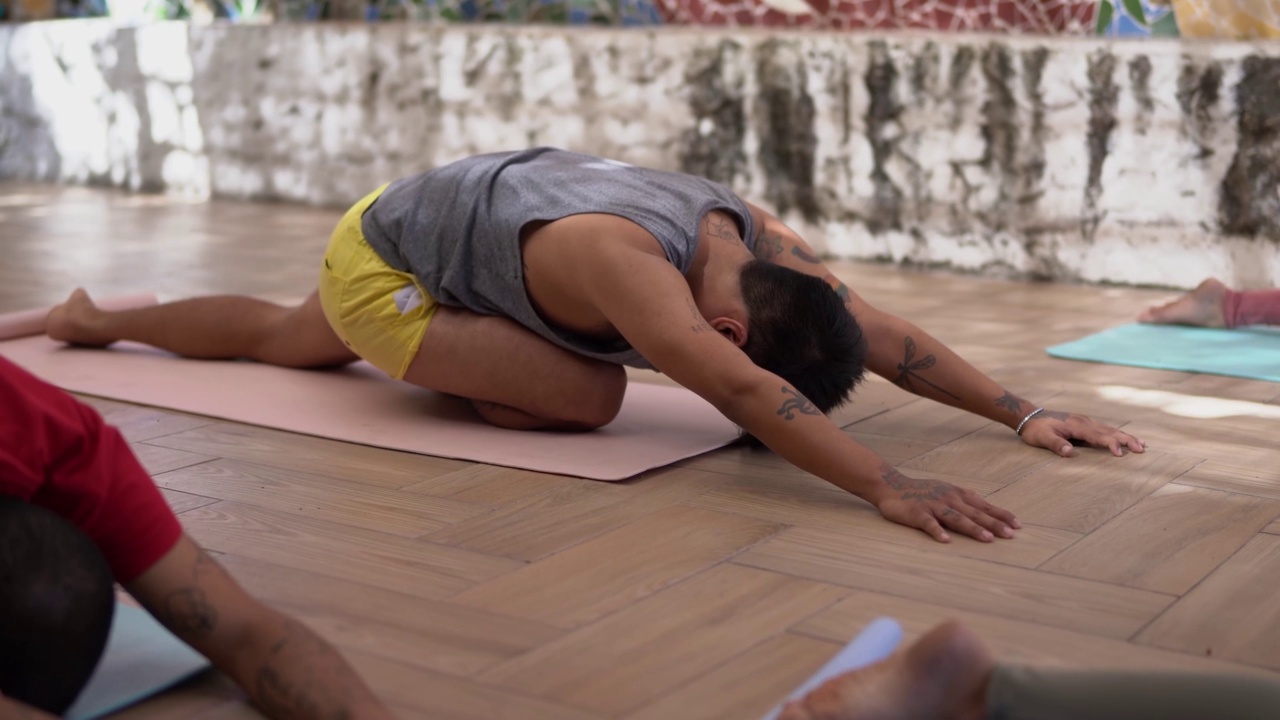 一个年轻人在瑜伽课上做伸展运动视频素材