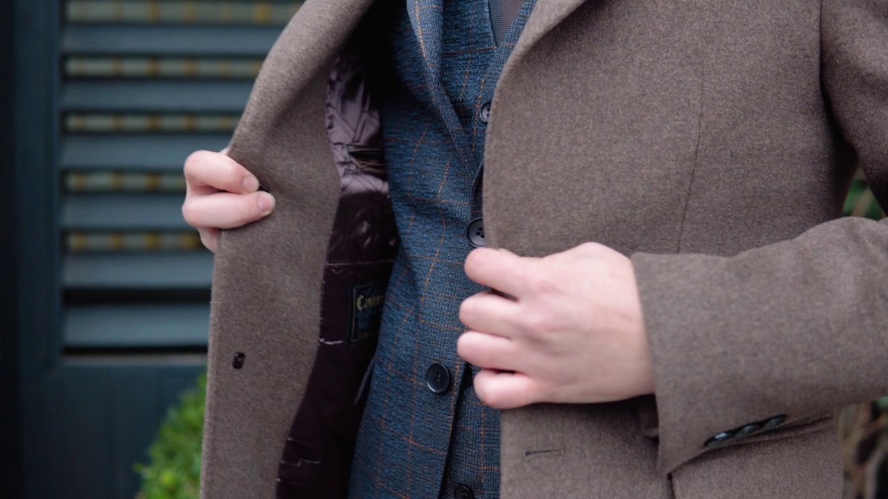 一个男人扣外套的特写。在办公中心附近，穿着棕色夹克和外套的年轻优雅的男性商人视频下载