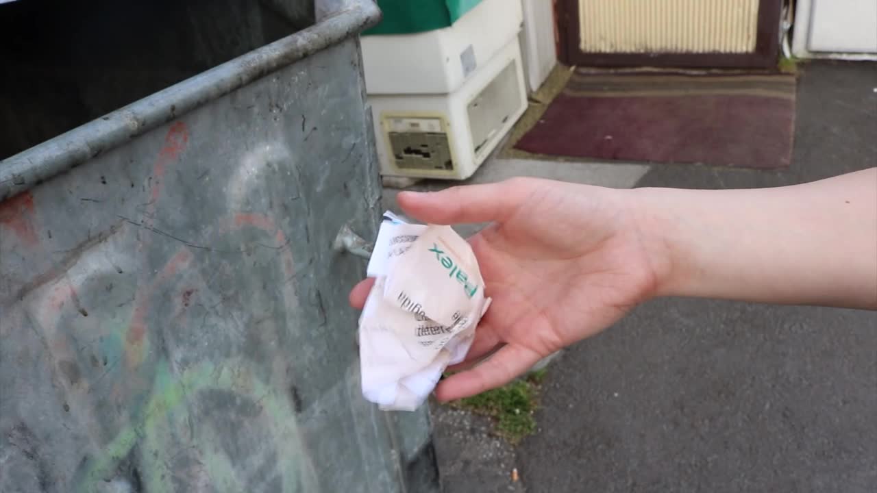 把皱巴巴的纸质垃圾扔进一个旧的垃圾桶里——年轻女性用手的动作来表达对回收和环境的关注视频下载