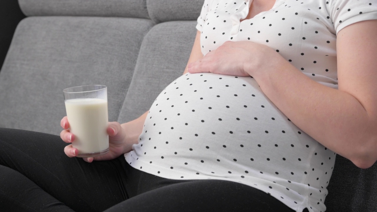 孕妇坐在沙发上喝着牛奶视频素材