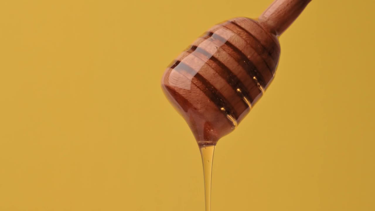 健康食品的概念。美味甜美的液体蜂蜜从黄色背景的木勺上流下来。有机健康蜂蜜，维生素，甜点。蜂蜜从勺子里滴下来视频素材
