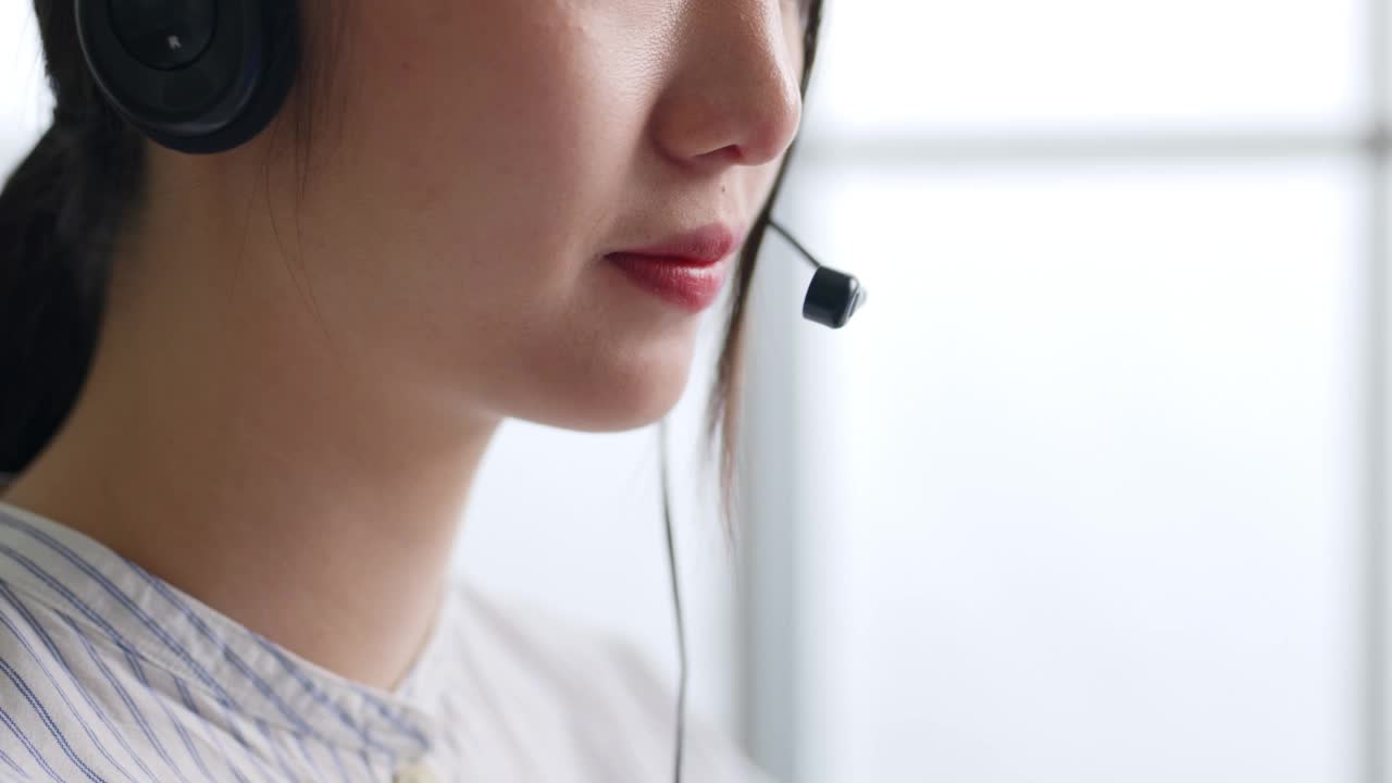 特写亚洲女性呼叫中心，客户服务，电话销售正装戴耳机或耳机在办公室与客户交谈视频素材
