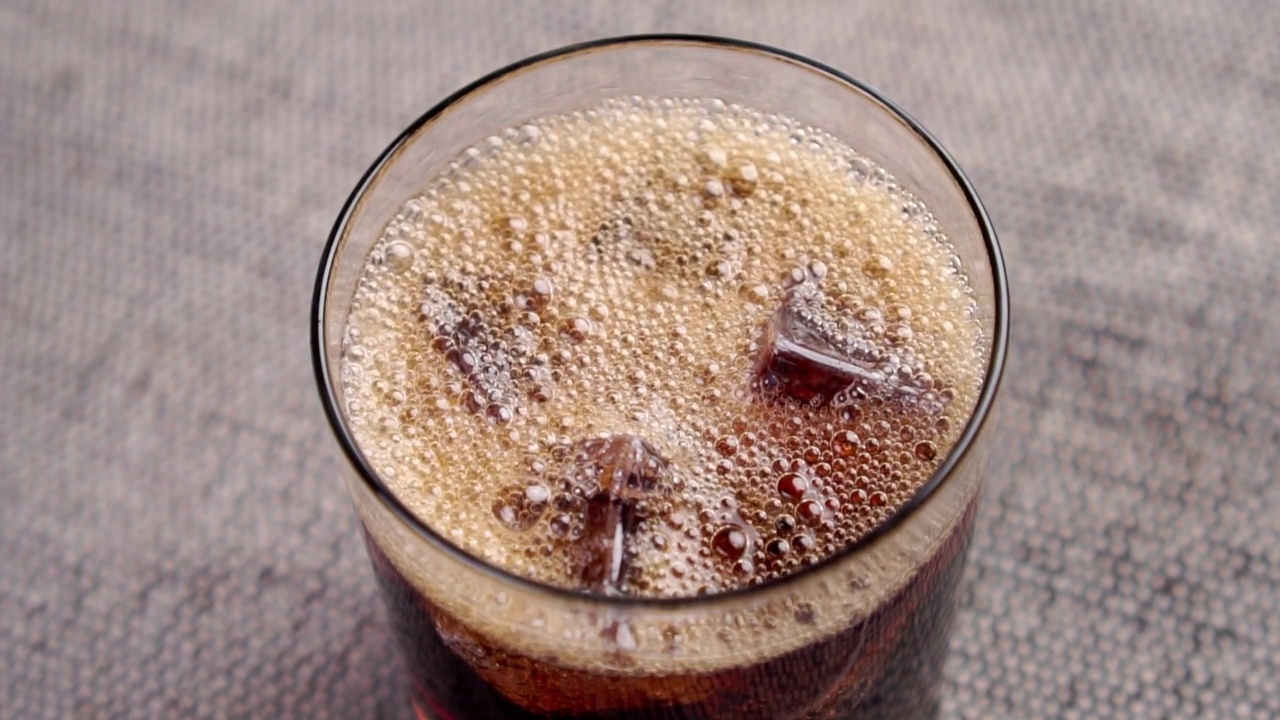 黑色碳酸可乐饮料在杯子与冰块的泡沫和泡沫。清凉冰饮料视频素材