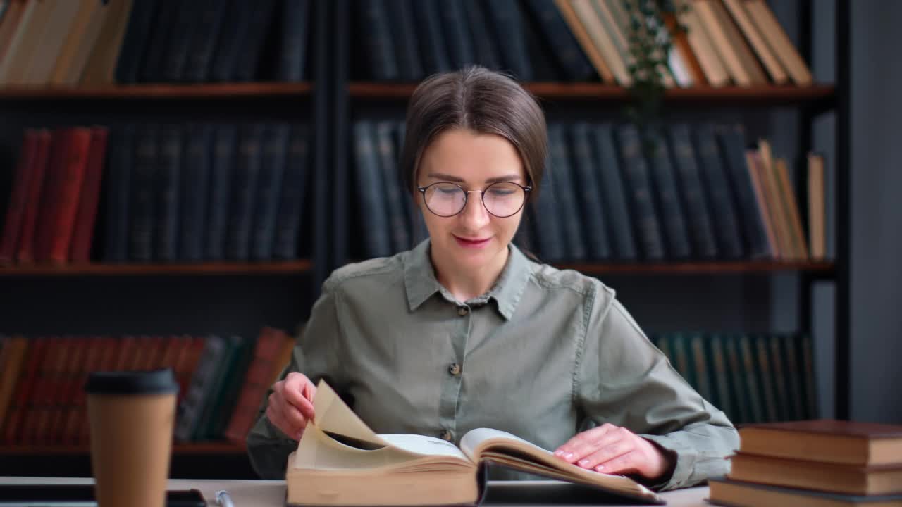 自信聪明的女人阅读古董纸质书翻页在公共图书馆书桌准备考试视频素材