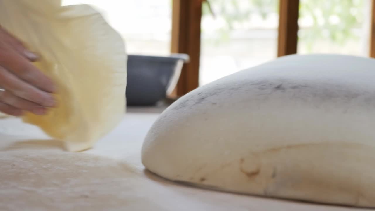 两个女面包师正在为全国皮塔饼准备一个薄薄的面团，用手把它展开，扔在一个搅拌垫上，准备做tonir。缓慢的运动。中东和亚美尼亚菜视频下载