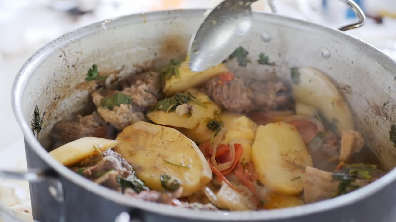从锅里取出一勺新鲜的亚美尼亚卡什喇嘛。根据一个古老的国家食谱，肉菜配蔬菜和香料。我们把食物视频下载