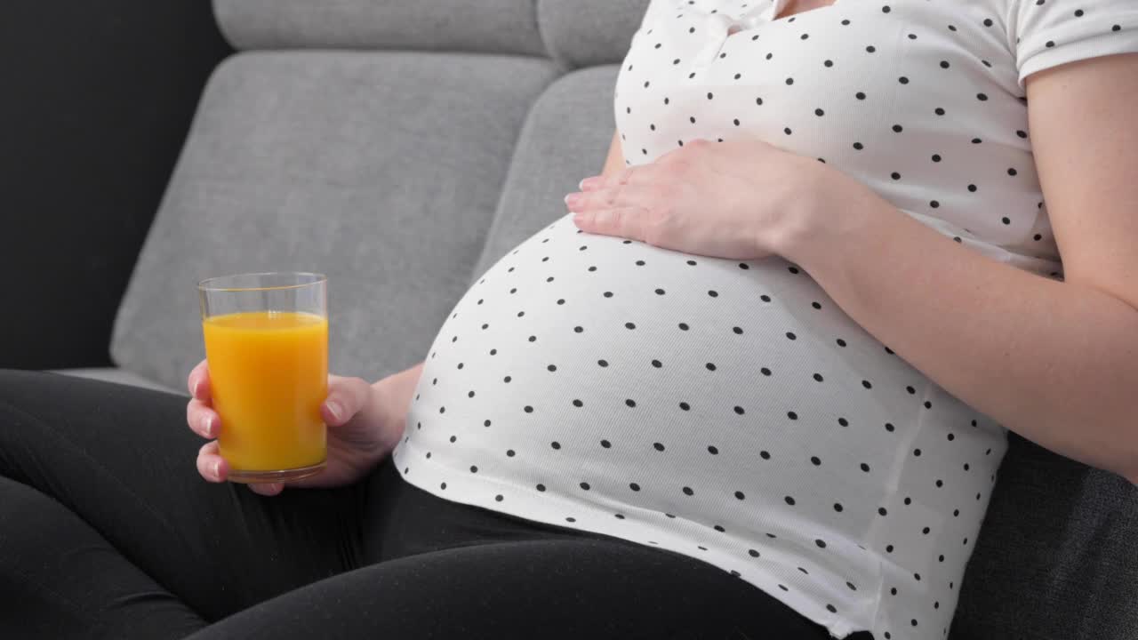 孕妇坐在沙发上喝着橙汁视频素材
