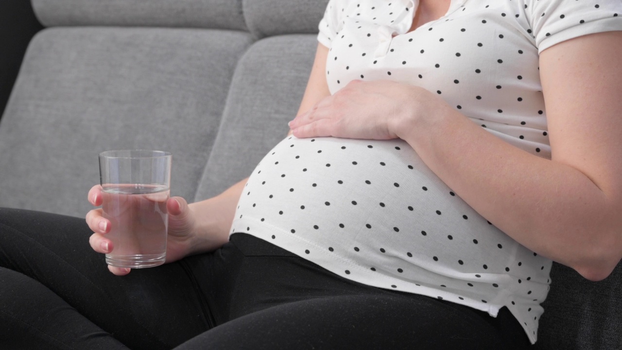 孕妇坐在沙发上，手里拿着一杯水视频素材