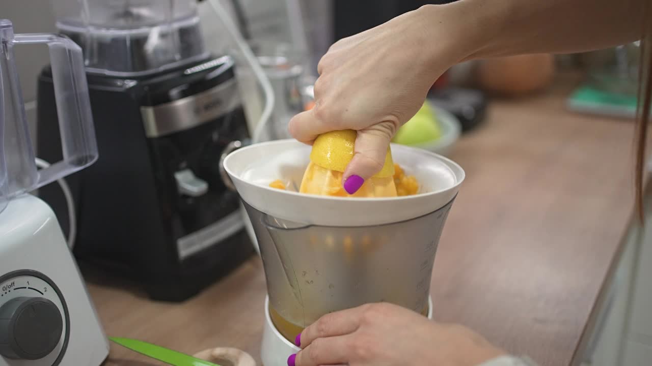 女性在家准备柠檬水时用榨汁机榨柠檬视频下载